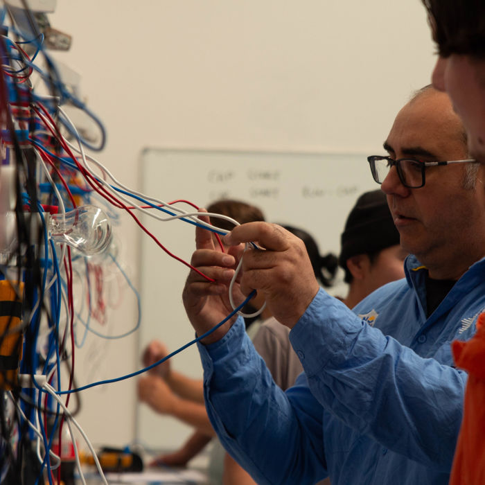 Trainer demonstrating electrical wiring on an electrotechnology training board.